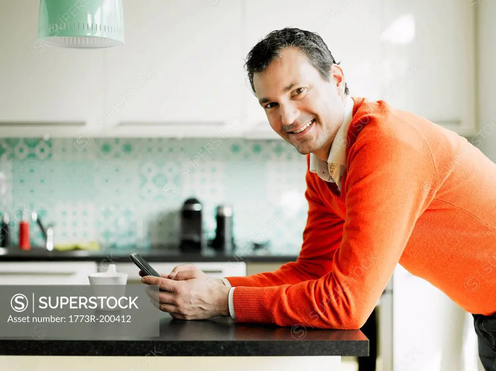 Portrait of mature man using cellphone in kitchen