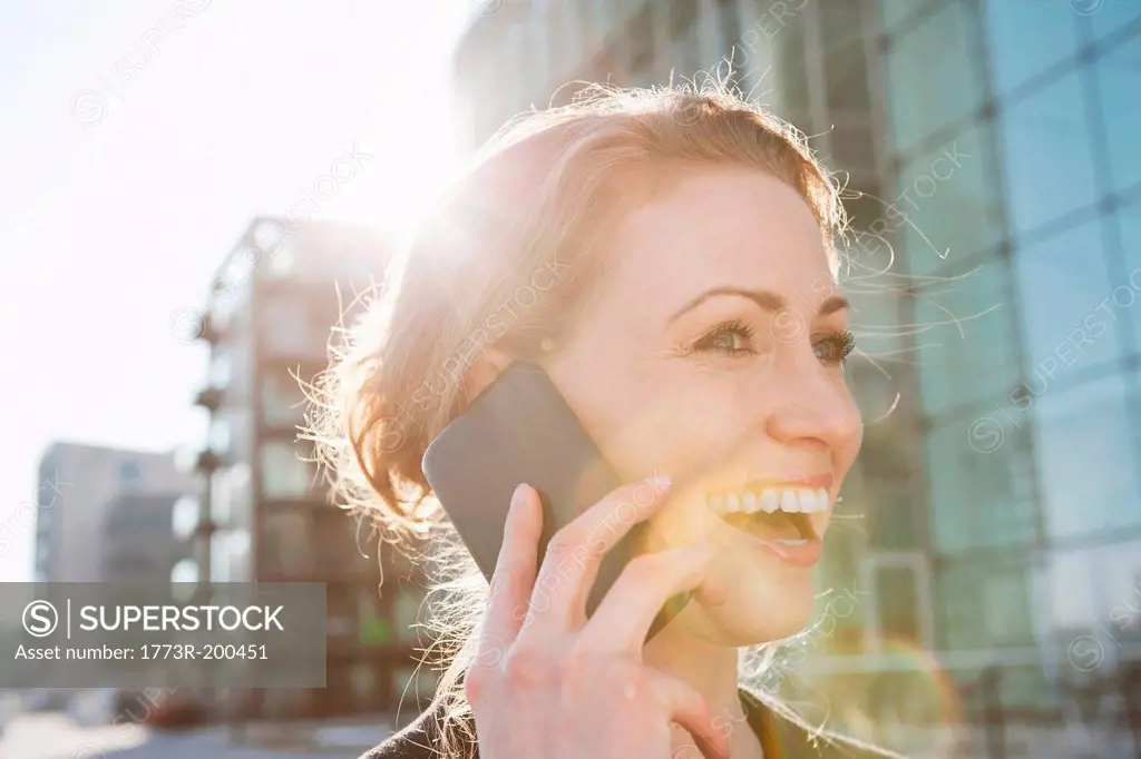 Mid adult woman using cellphone in sunlight outdoors