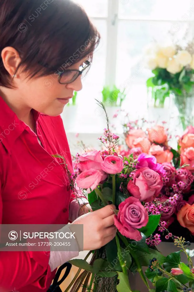 Young woman arranging fresh flowers into bouquet