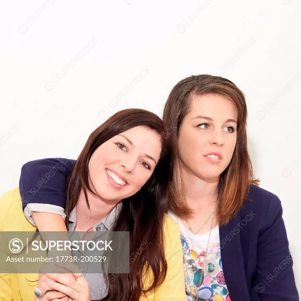 Young woman looking unimpressed next to friend against white background