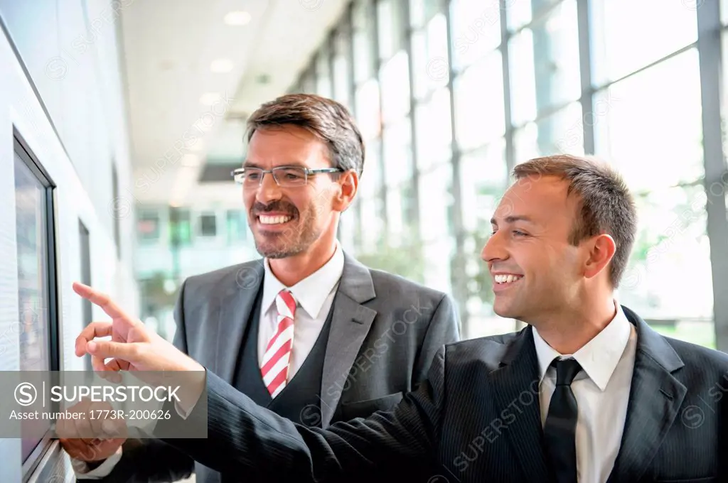 Businessmen pointing and looking at wall screen