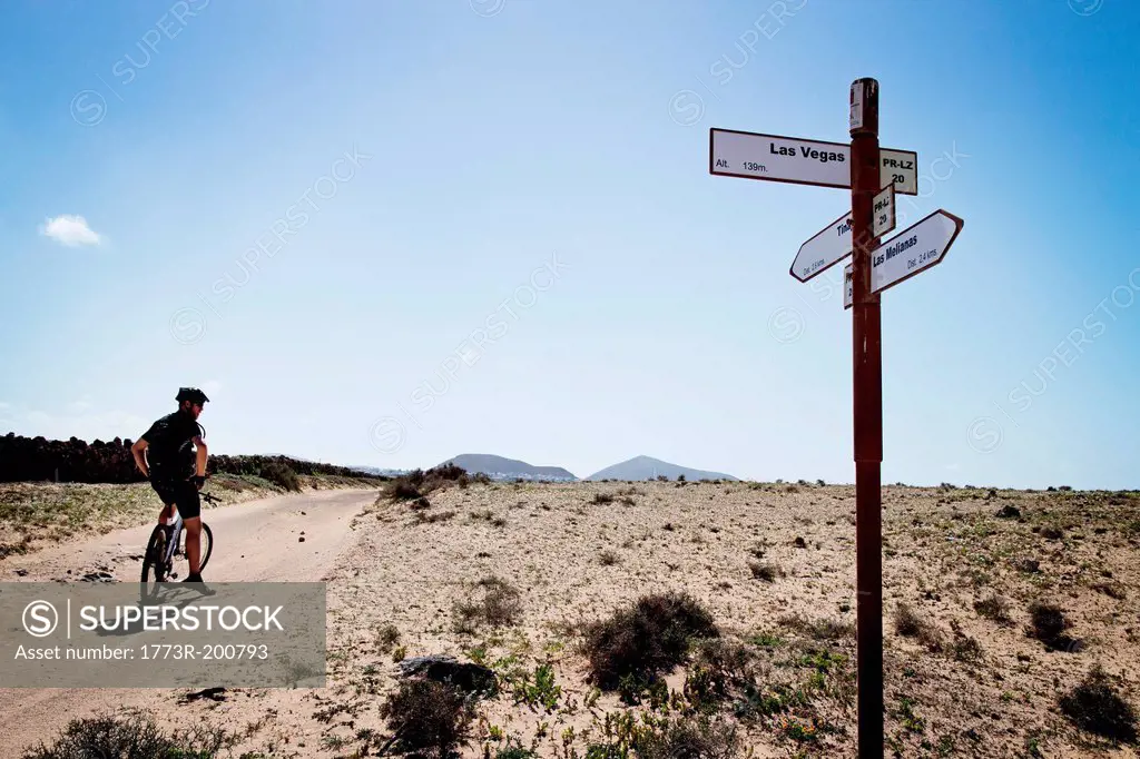 Man mountain biking past sign post, Lanzarote