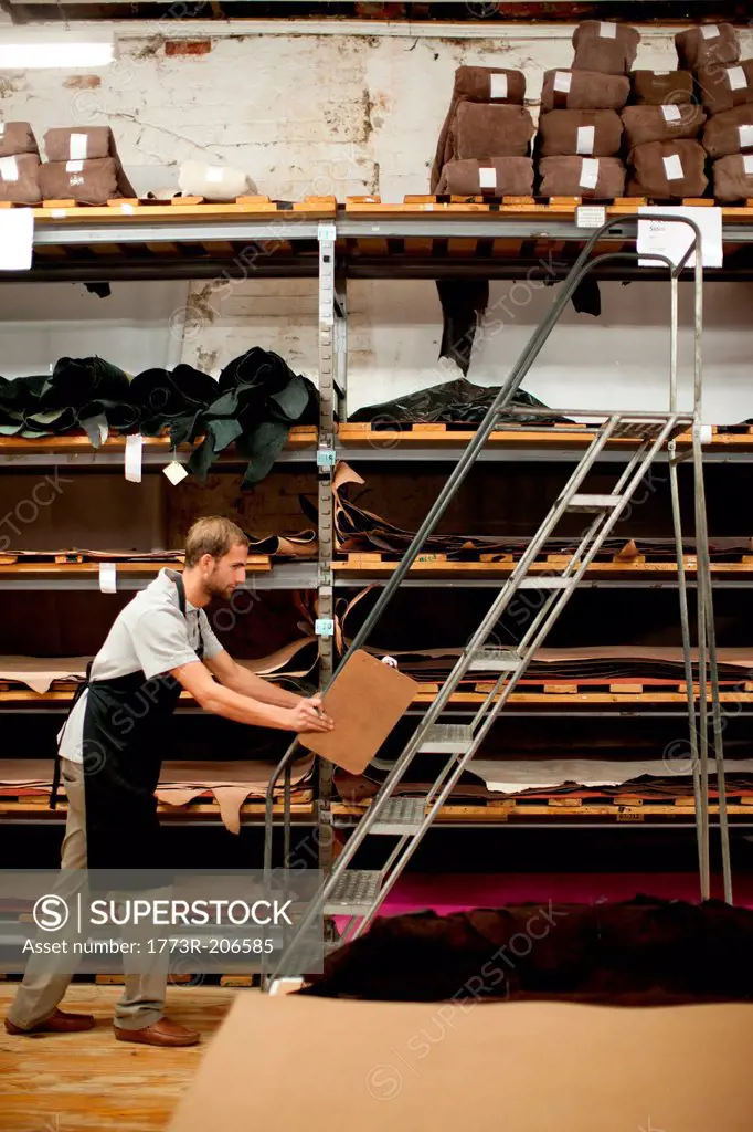 Young man working in leather stockroom