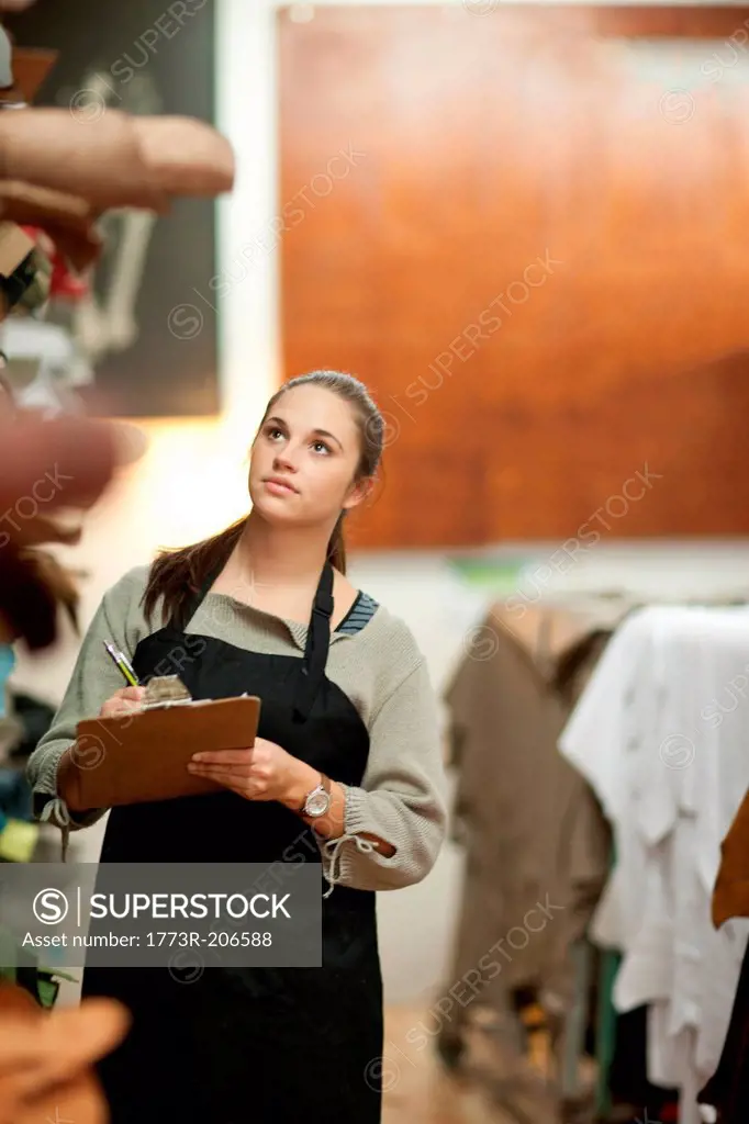 Young woman working in leather stockroom