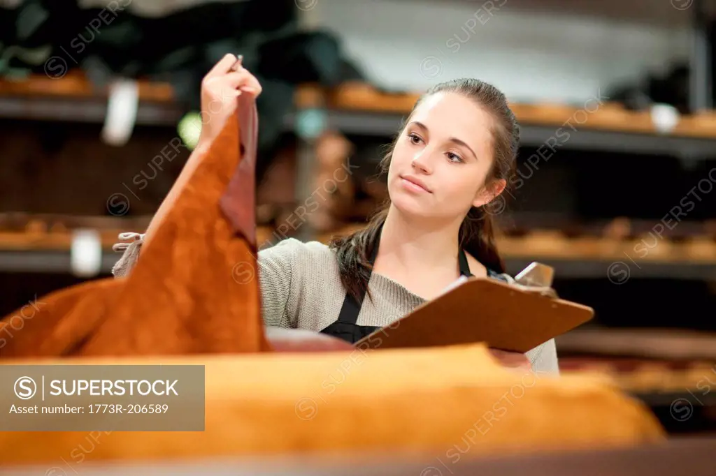 Worker looking at roll of leather