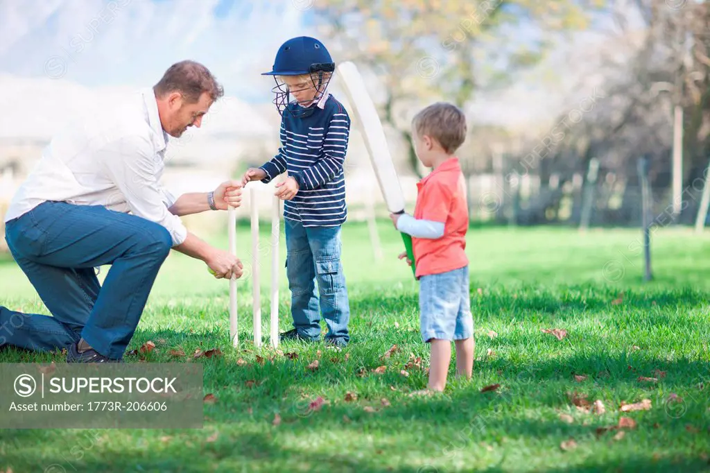 Father and sons preparing stumps for cricket