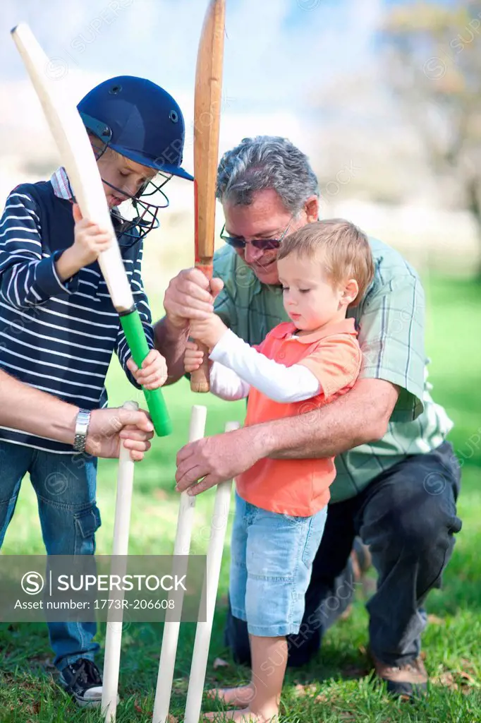 Boys and grandfather preparing stumps for cricket