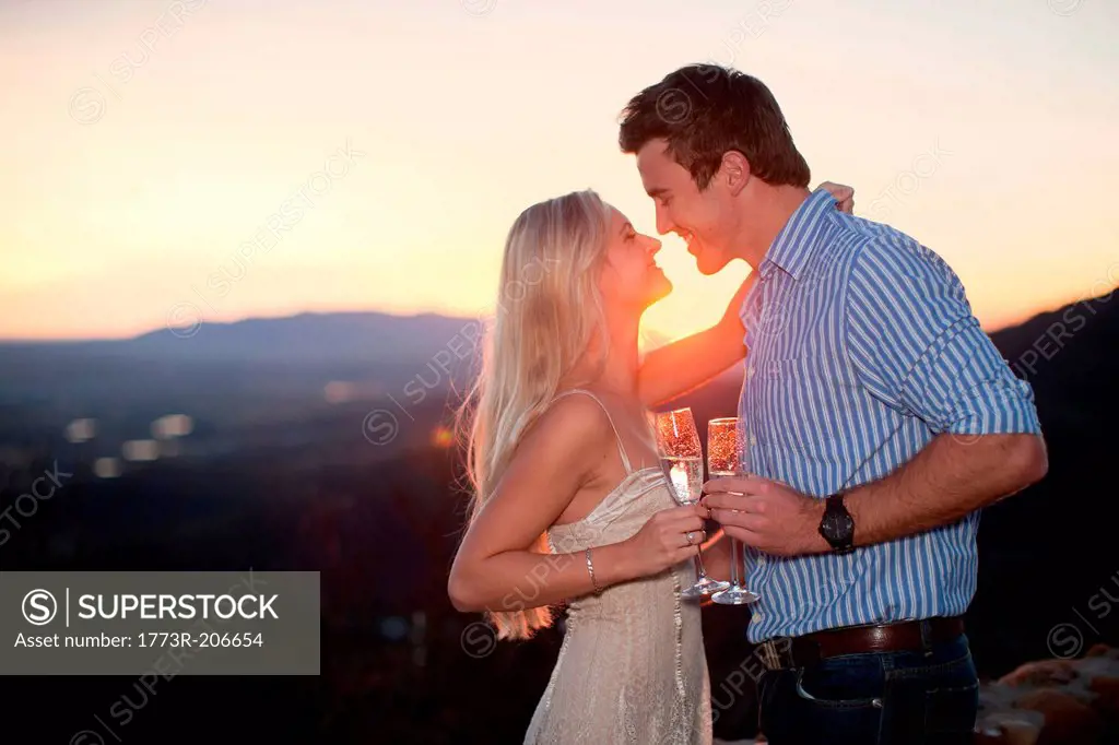 Affectionate couple having champagne outdoors at sunset