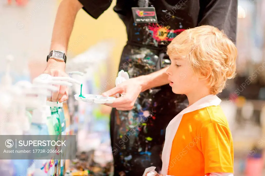 Man helping boy get paint to use