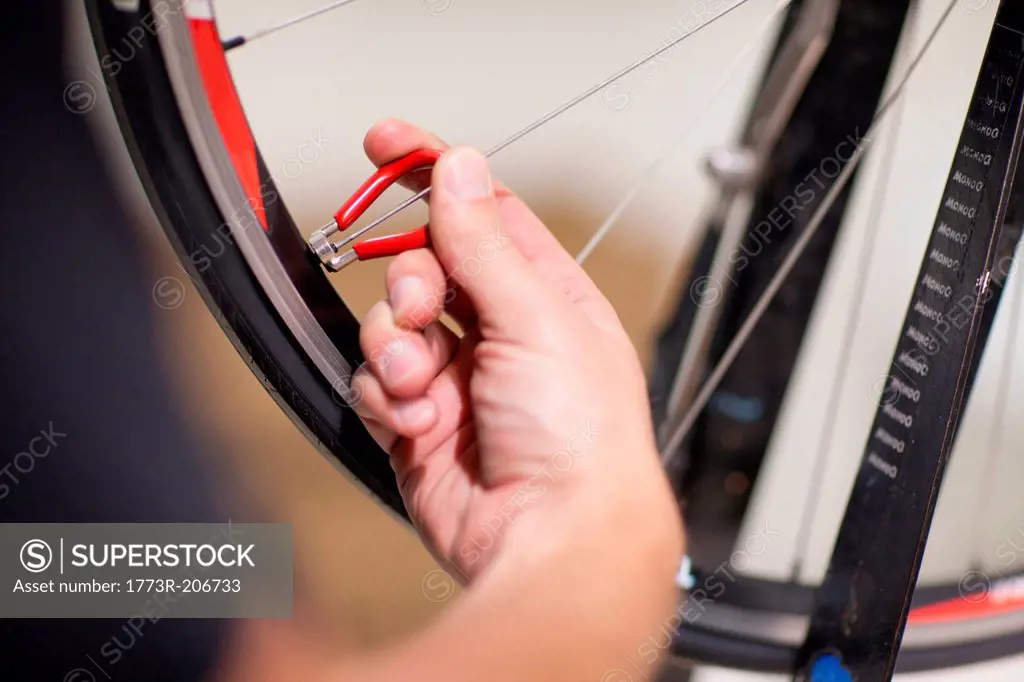 Close up of person using spoke wrench on bicycle wheel