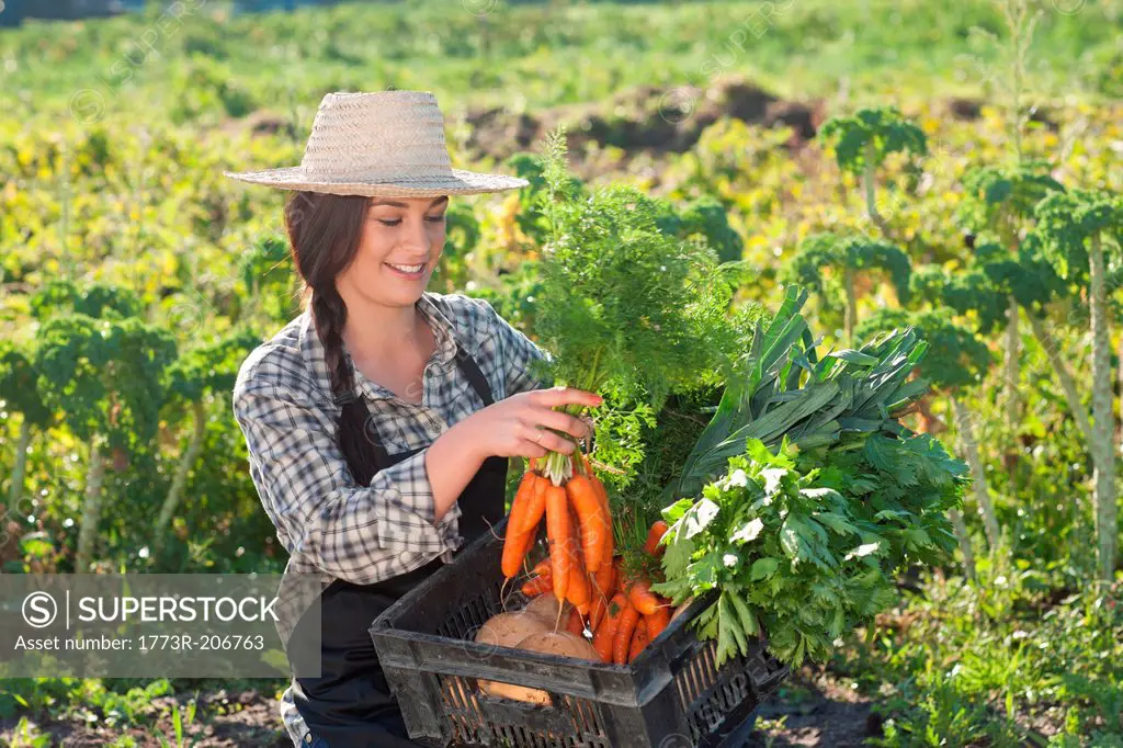 Young woman with vegetables grown at farm
