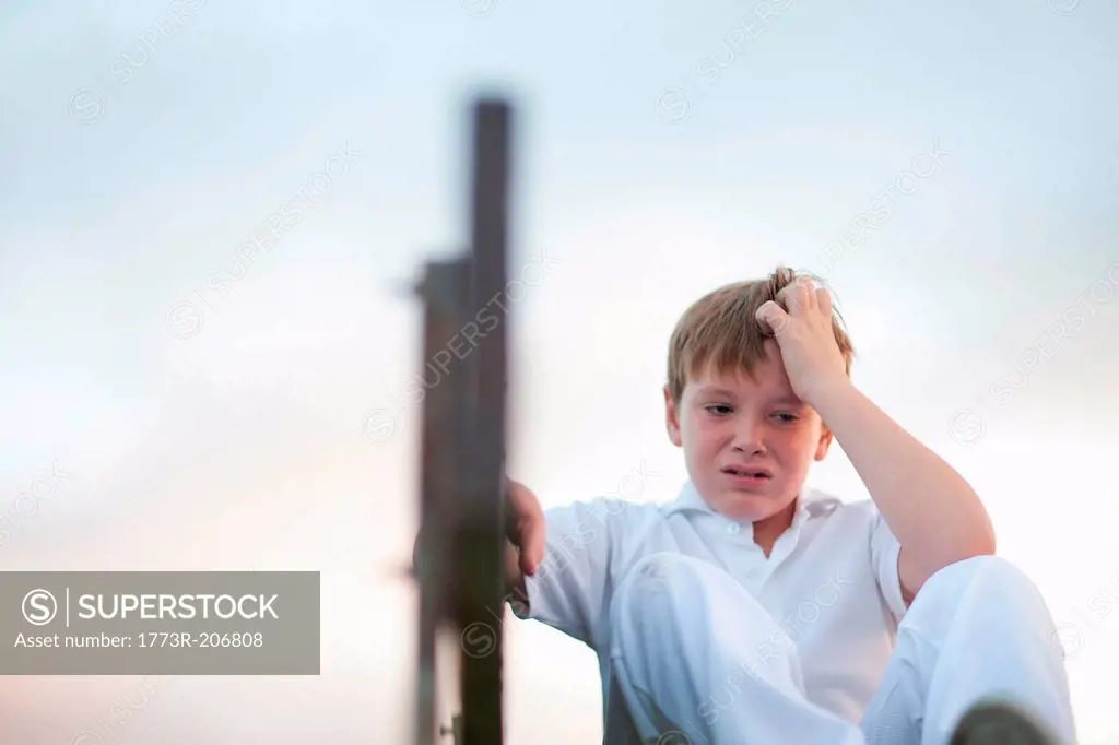 Boy on bleachers at cricket pitch scratching head