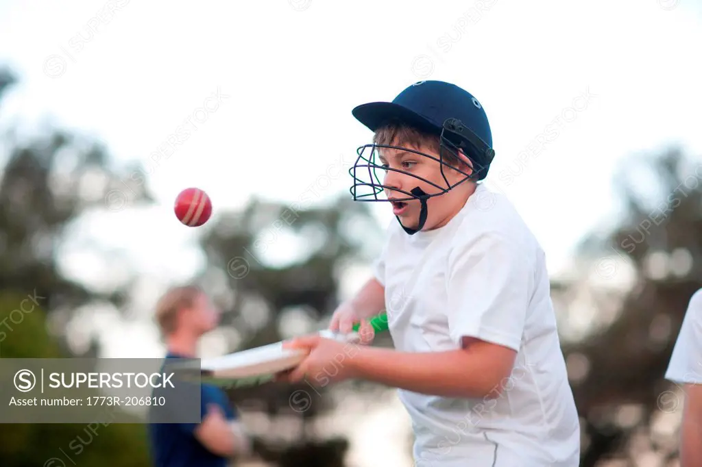 Boy practising hitting cricket ball with bat