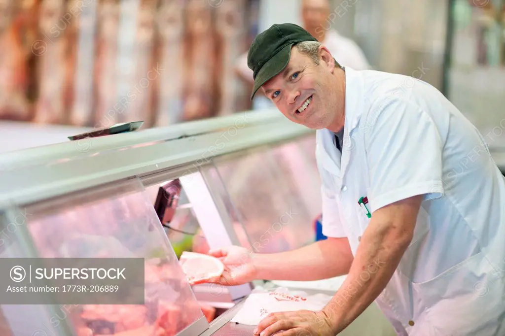 Butcher choosing meat from cabinet
