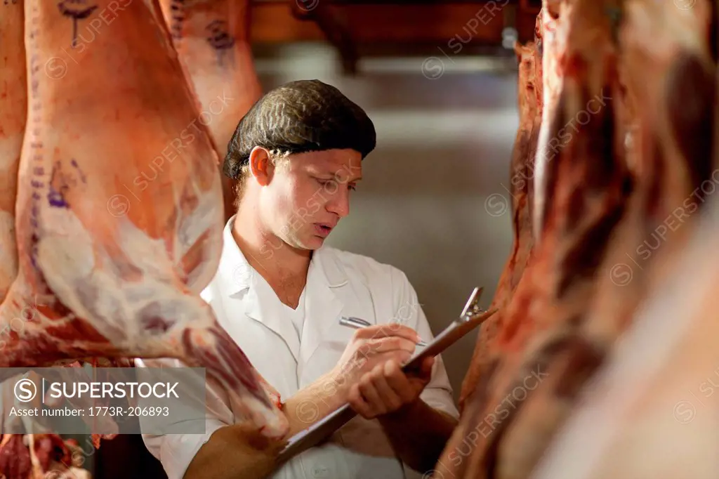 Butcher with clipboard inspecting meat
