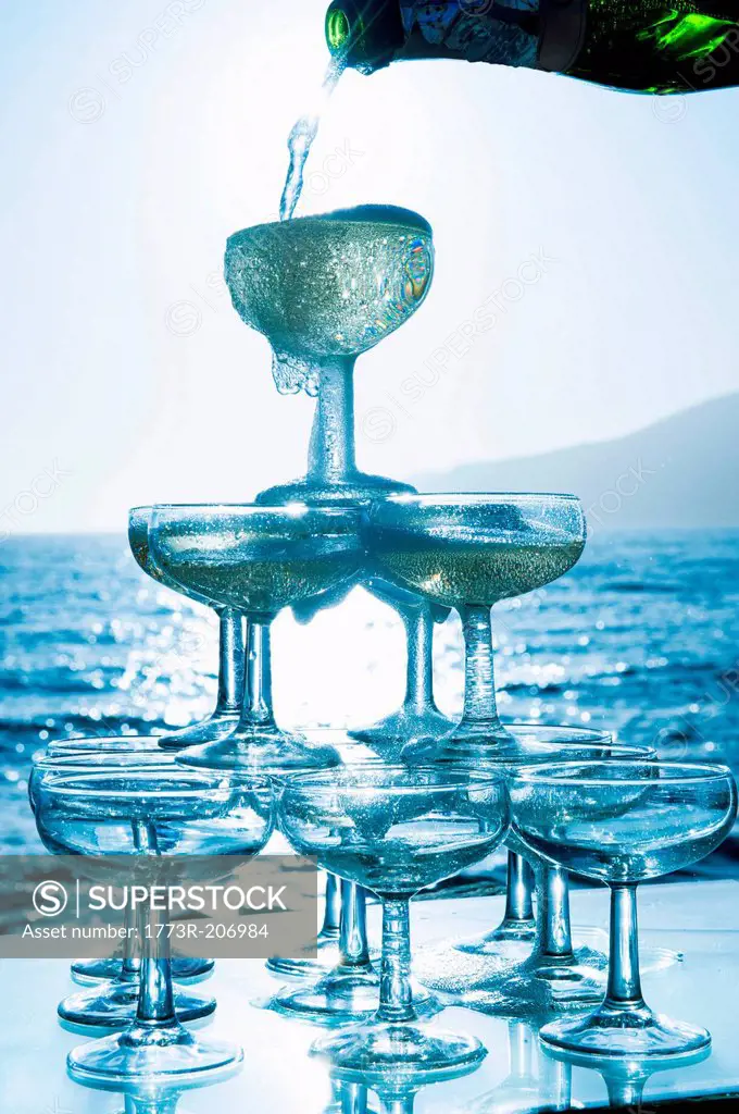 Champagne pouring into glasses with sea in background