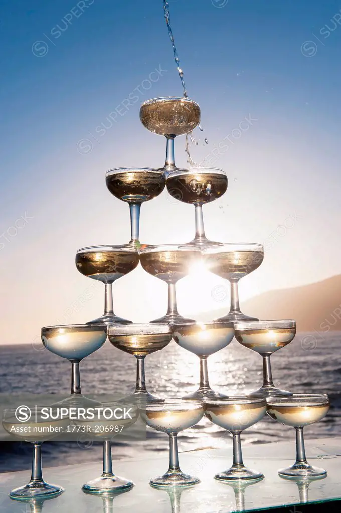 Champagne pouring into glasses with sea in background