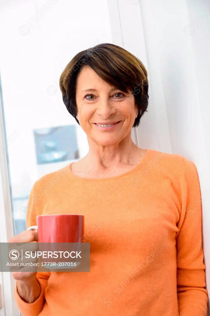 Woman holding mug of coffee, smiling