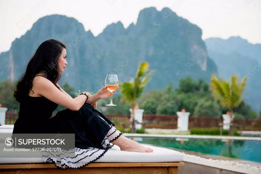 Woman with wine glass by poolside, Vang Vieng, Laos