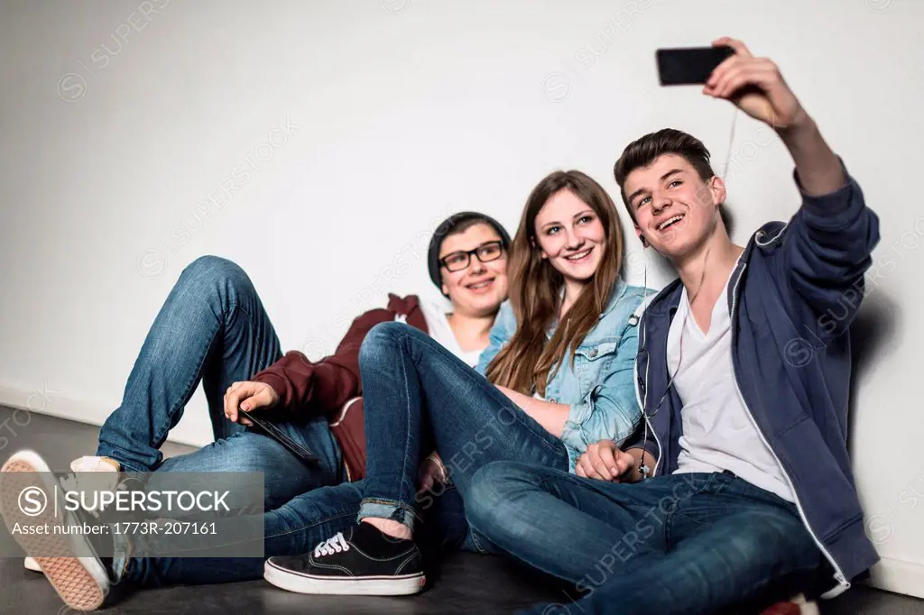 Three teenagers taking self portrait photograph using smartphone