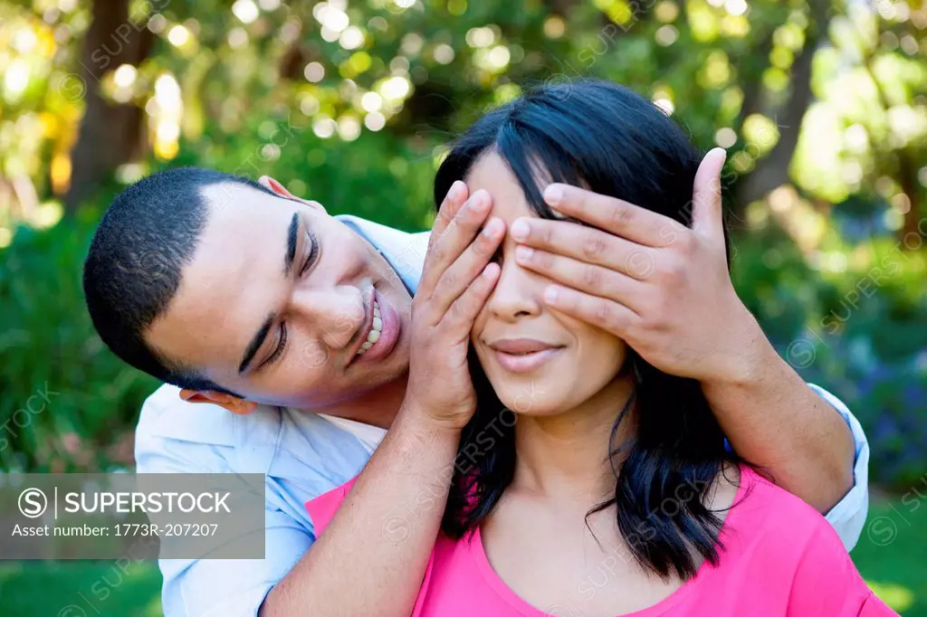 Young man covering woman's eye