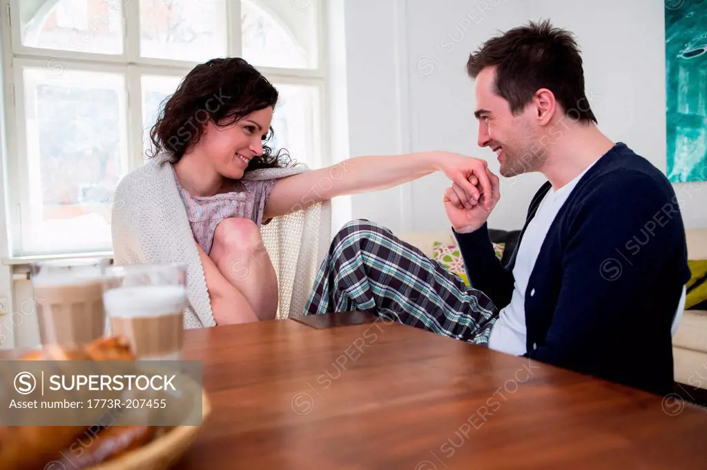 Heterosexual couple holding hands at breakfast table