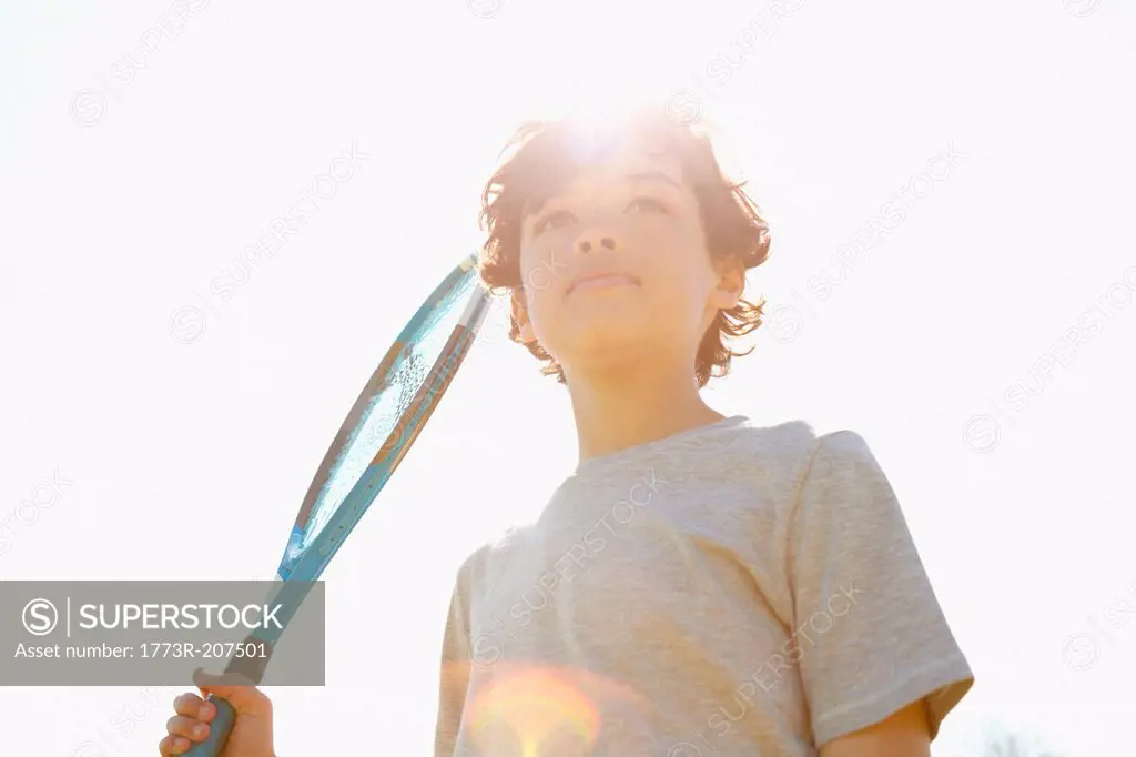 Boy holding up tennis racket