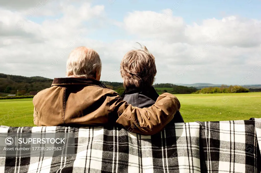 Back view of senior couple enjoying scenery on field