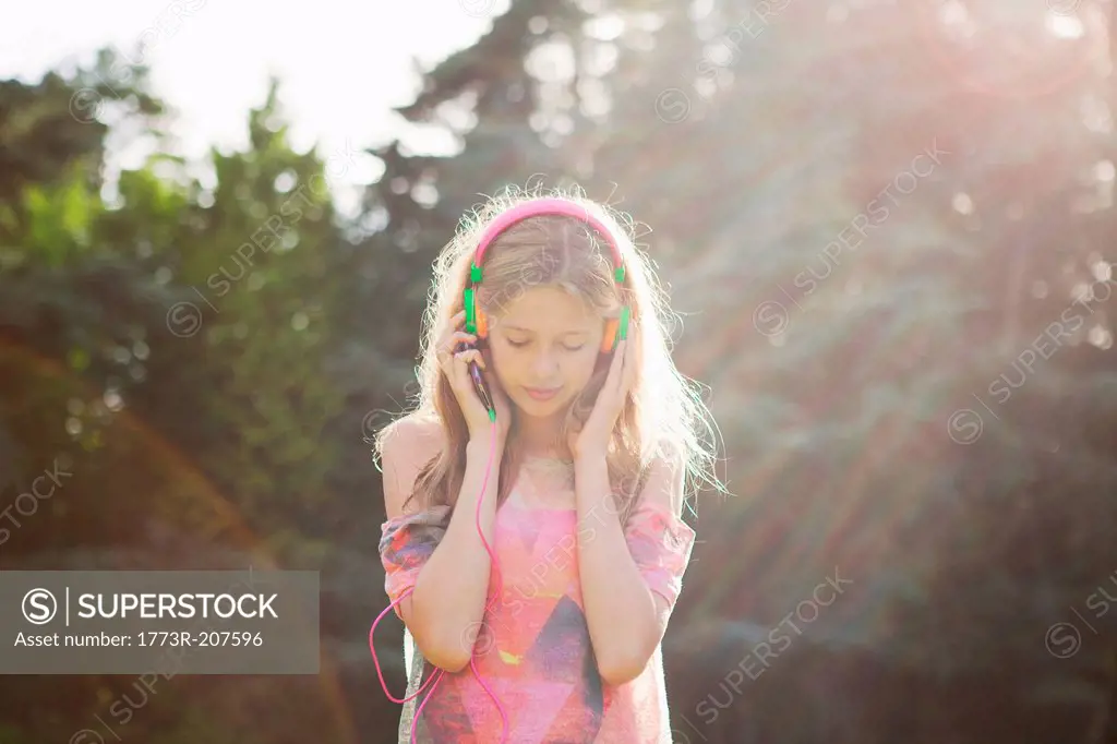Teenage girl wearing headphones in sunlight