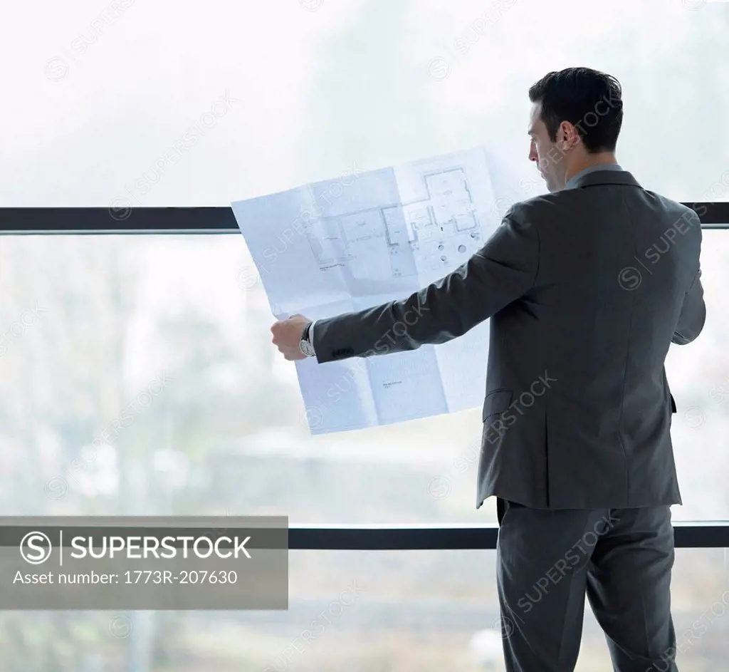 Architect inspecting plans by office window