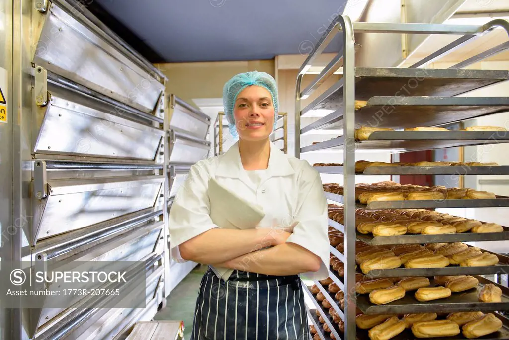 Baker standing by racks of baked pastries, portrait