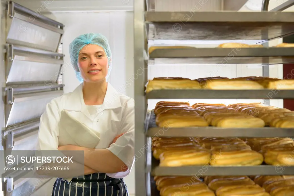 Baker standing by racks of baked pastries, portrait