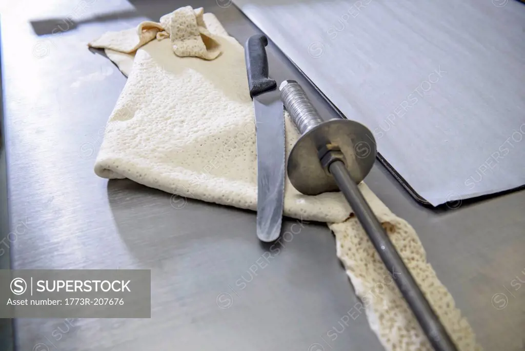 Offcut of dough, knife and rolling instrument in bakery