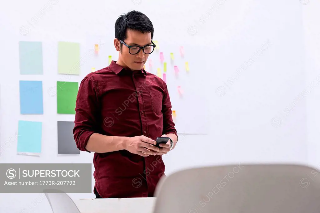 Young male with smartphone in design studio