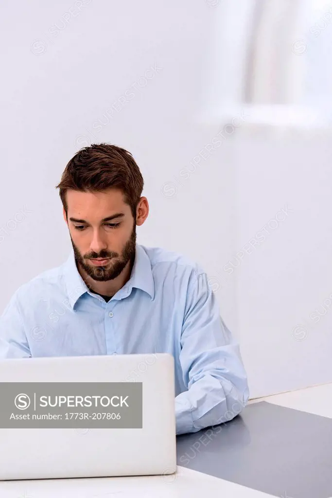 Young man sitting behind laptop in office