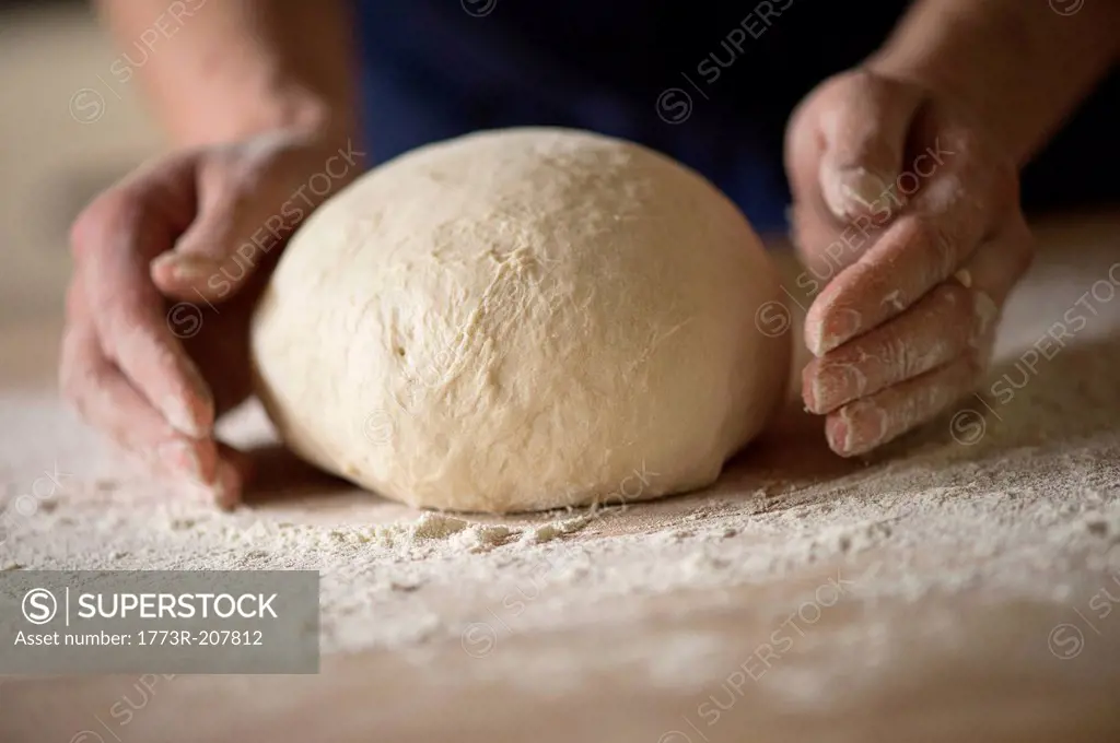 Close up of hands shaping bread dough