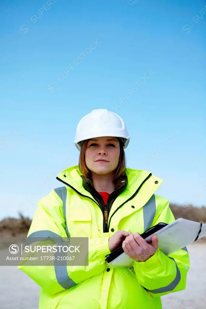 Portrait of female outdoors holding file and digital tablet