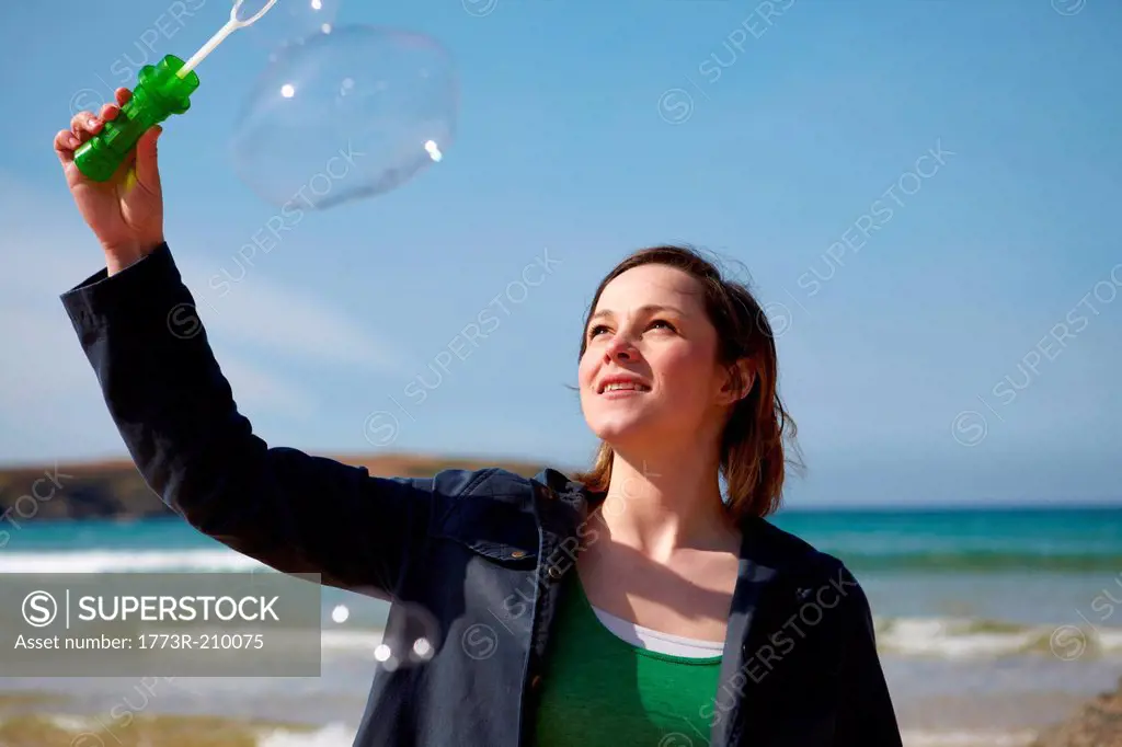 Young woman at coast with bubble wand