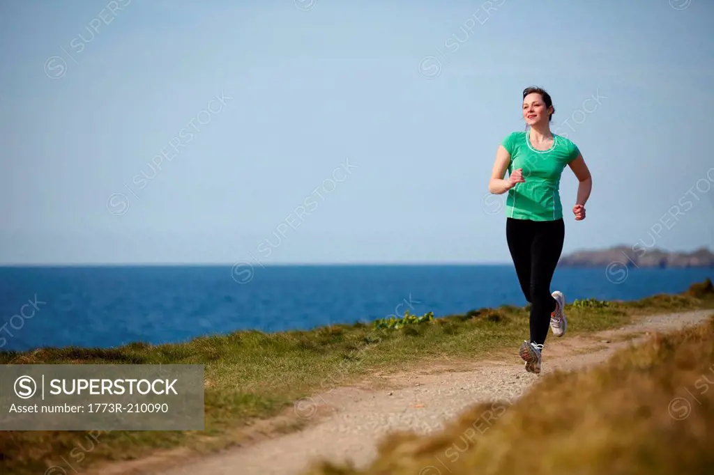 Young woman running along coastal path
