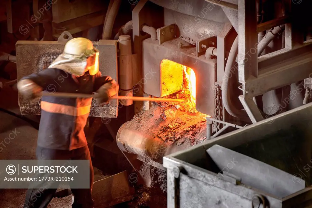 Steel worker poking furnace in steel foundry