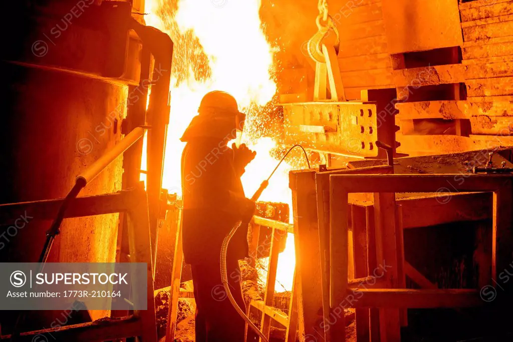 Steel worker in front of furnace fire in steel foundry