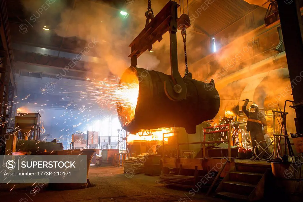 Steel worker and bucket of molten metal in steel foundry
