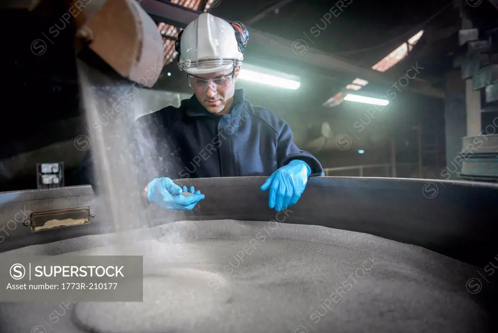 Worker checking container of steel shot in steel foundry