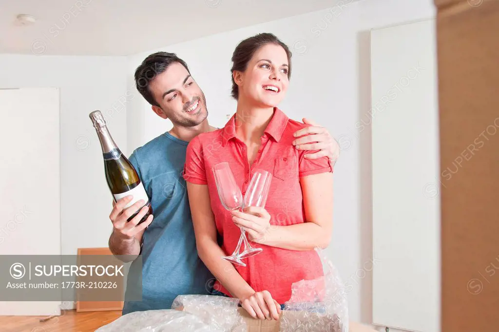 Young couple celebrating house move with champagne