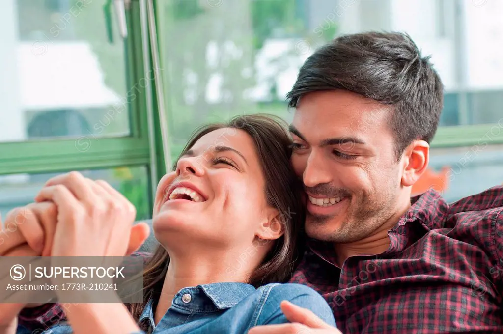 Romantic young couple laughing on sofa