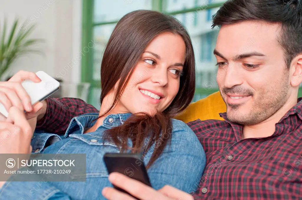 Young couple at home using mobile phones