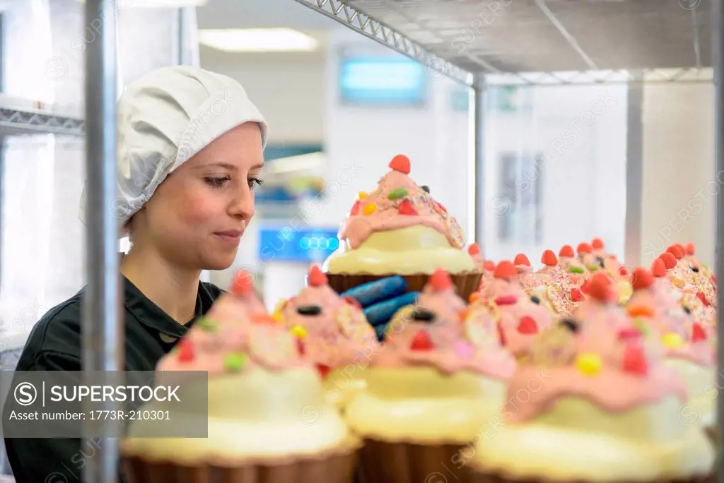 Chocolatier arranging giant chocolate cupcakes in sweet factory
