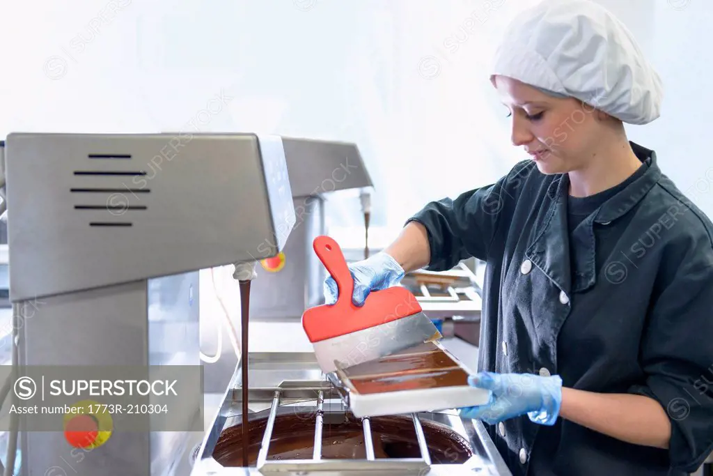 Chocolatier smoothing chocolate in moulds