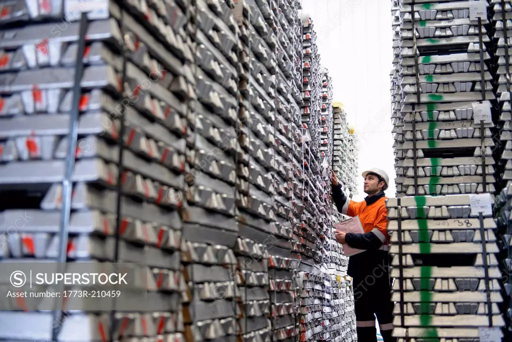 Warehouse worker checking stacked aluminum ingots