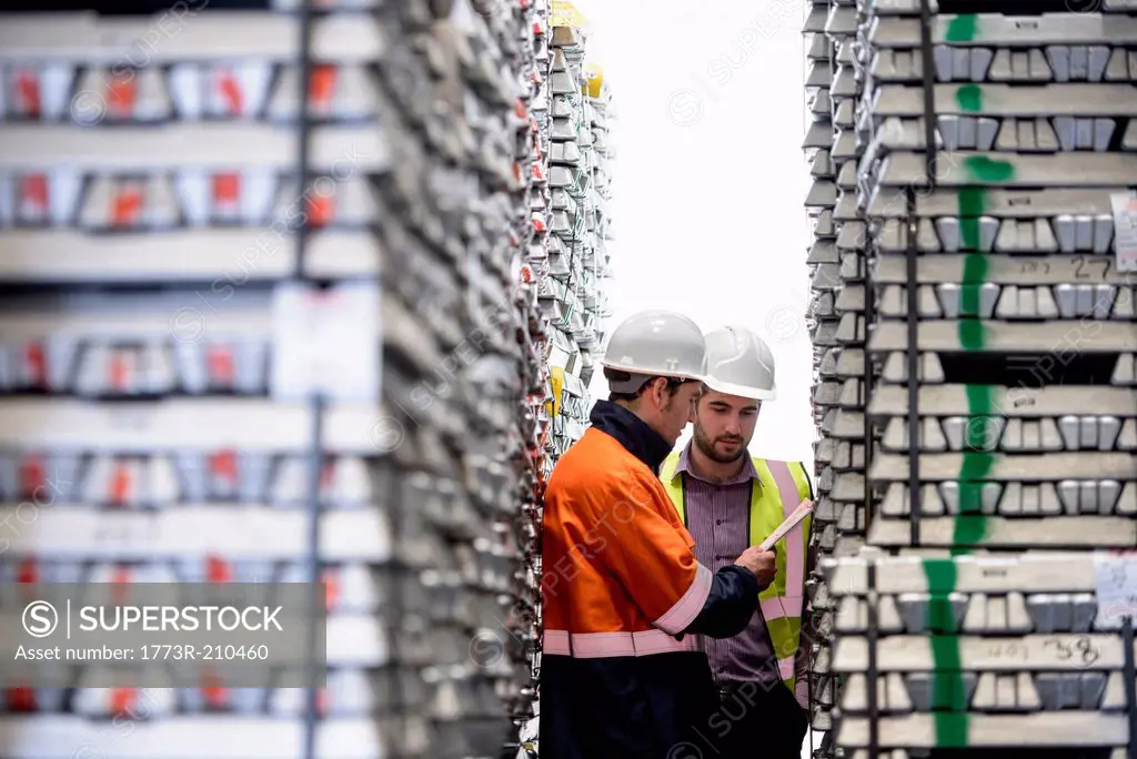 Warehouse workers checking stacked aluminum ingots